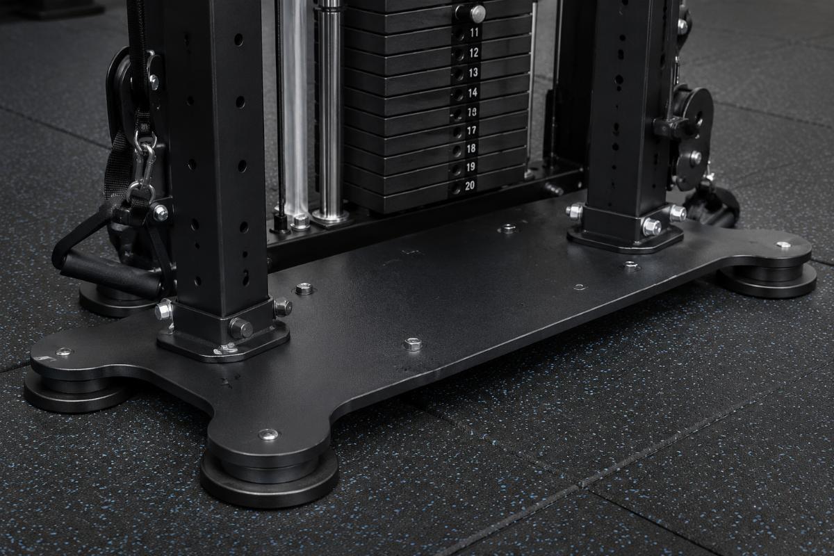 Close-up of a functional trainer base plate showing wide footprint and multi-point contact on rubber gym flooring