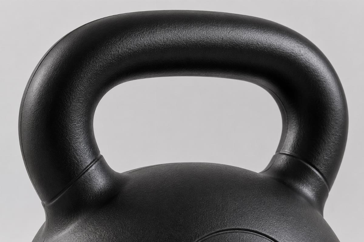 Close-up of commercial kettlebell handle showing smooth horn transition radius and controlled matte surface finish