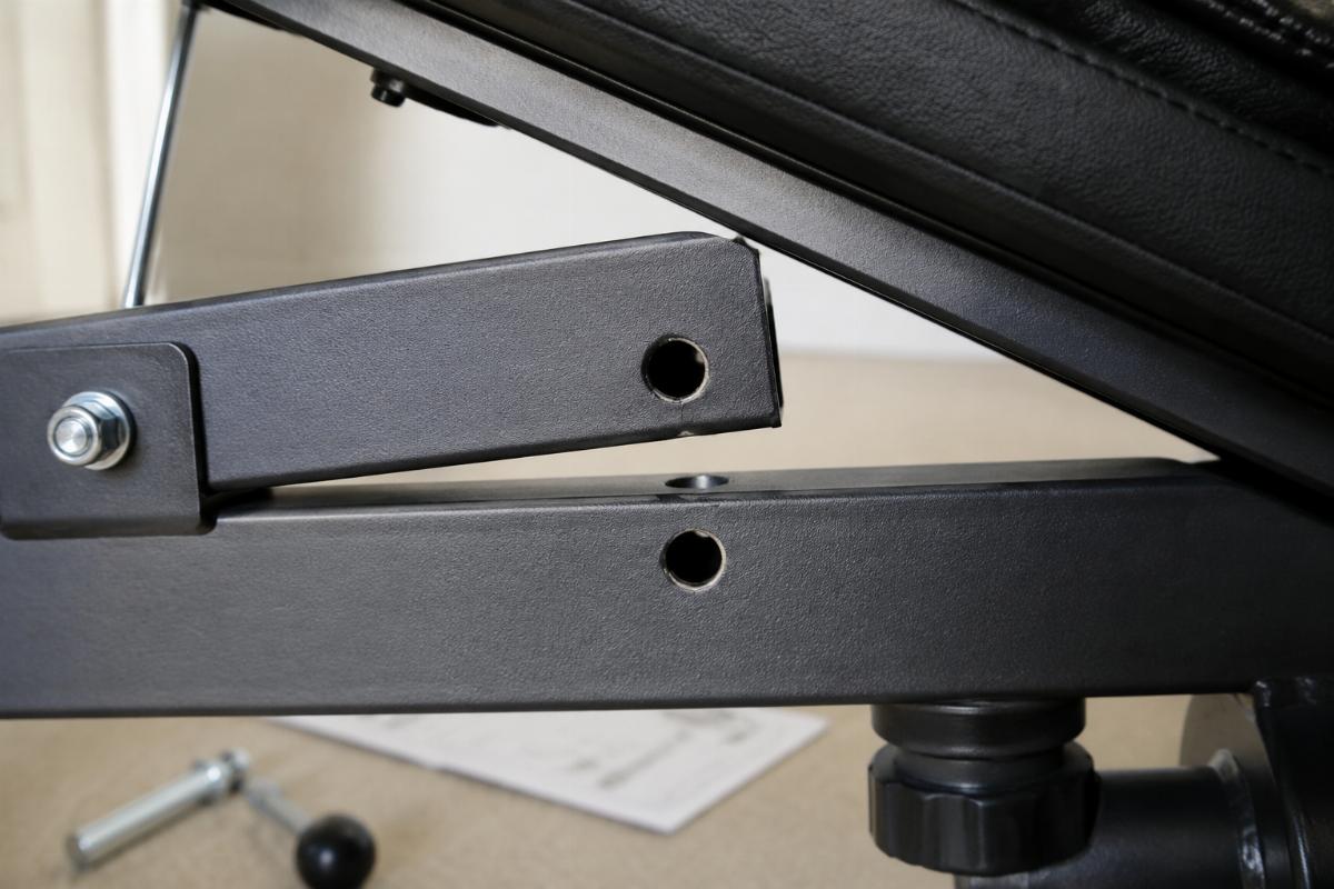 Close-up of misaligned adjustment pin holes on an adjustable bench frame during failed assembly