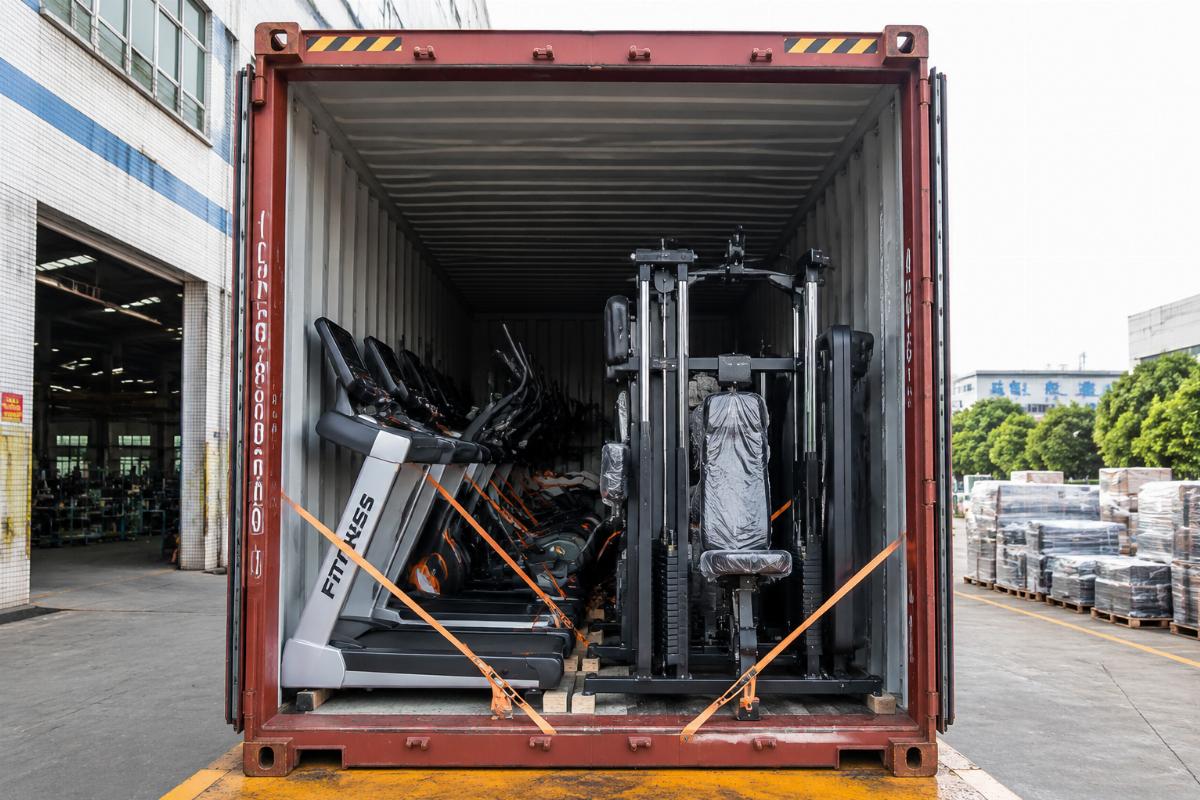 Commercial gym exercise equipment loaded into a 40HQ container at the factory, showing cardio machines and strength stations secured for ocean freight