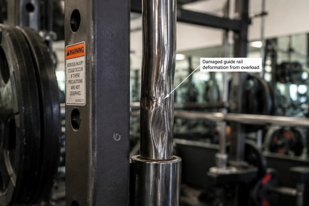 Damaged Smith machine guide rail showing deformation from overload conditions