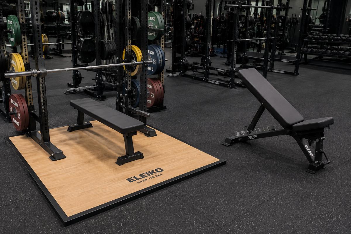 Flat bench press bench on powerlifting platform alongside adjustable bench in general training zone