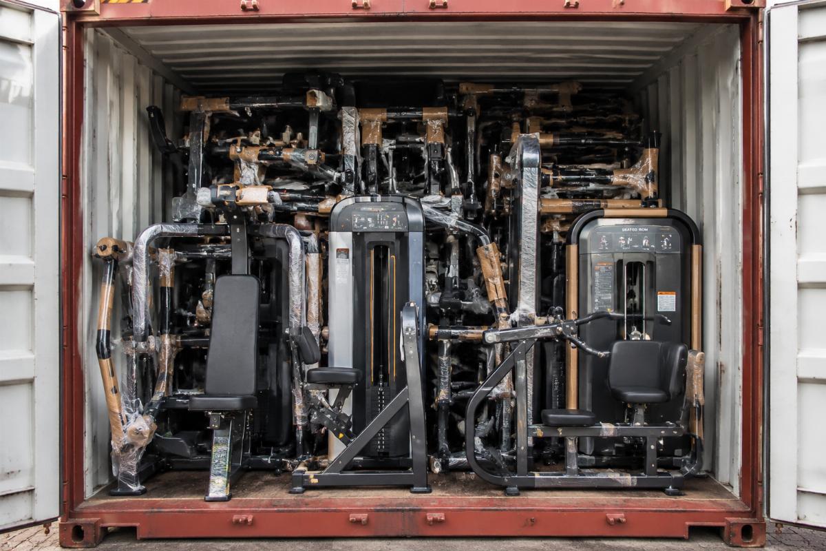 Full container loaded with mixed commercial gym equipment including seated row machines