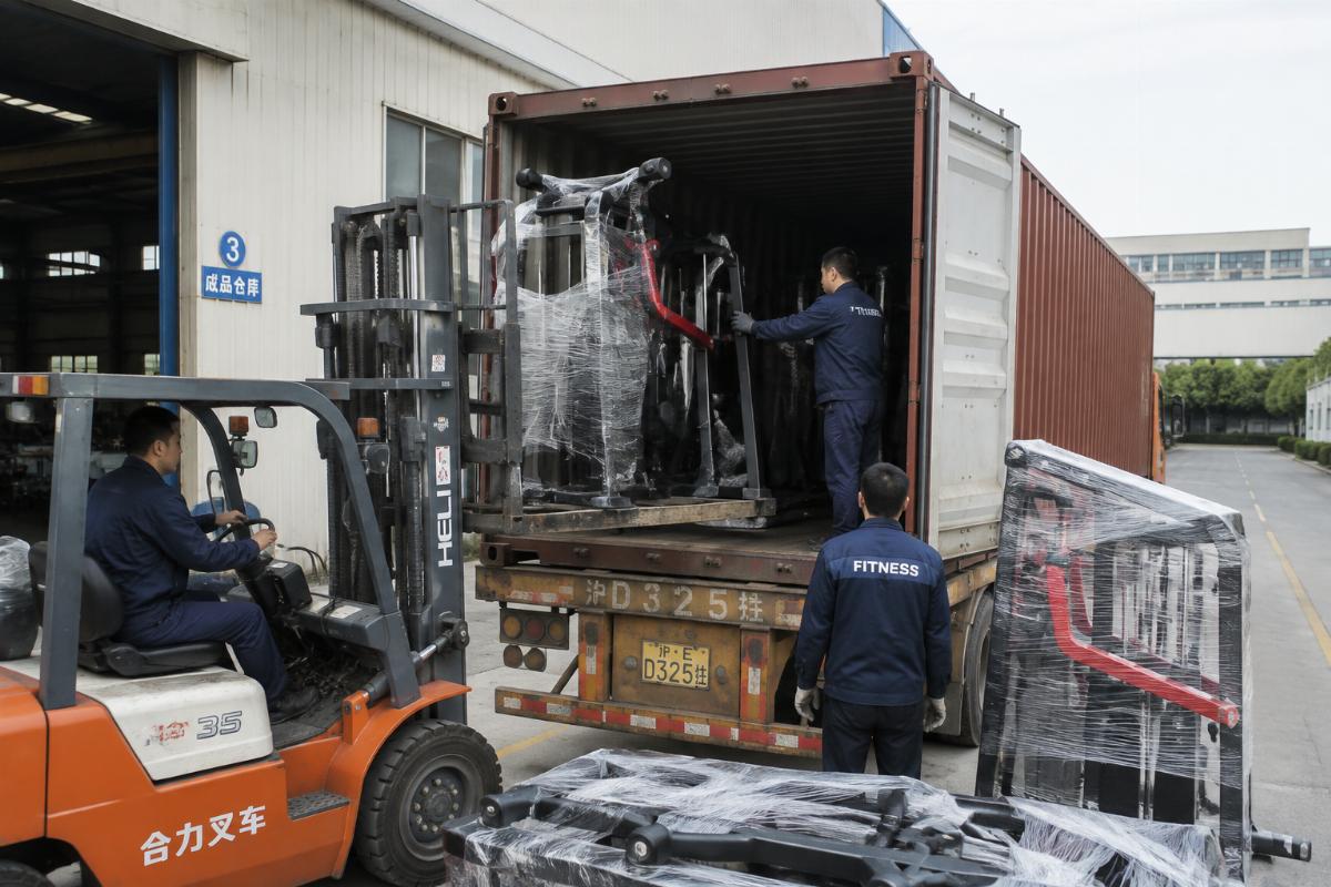 Mixed gym equipment being loaded into a shipping container at factory dock