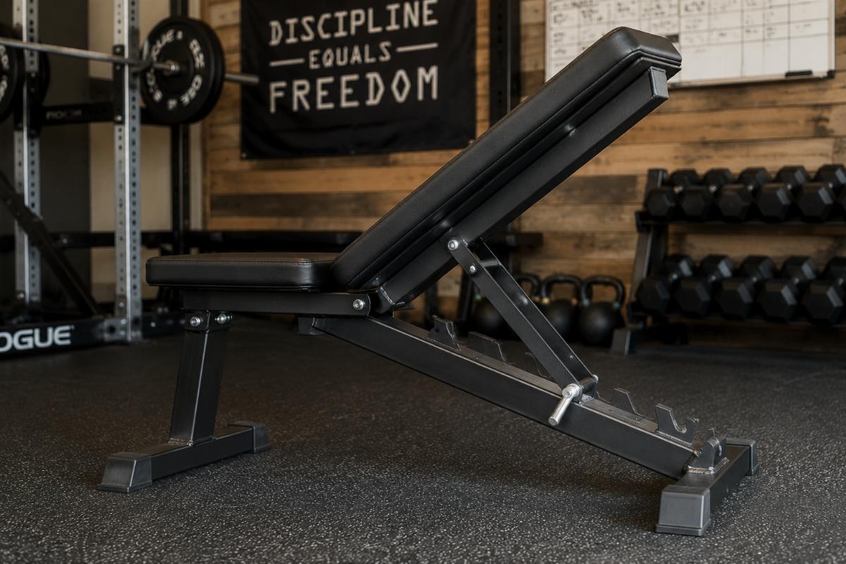 Side view of a commercial utility bench showing weld joints and adjustment mechanism in a small gym setting